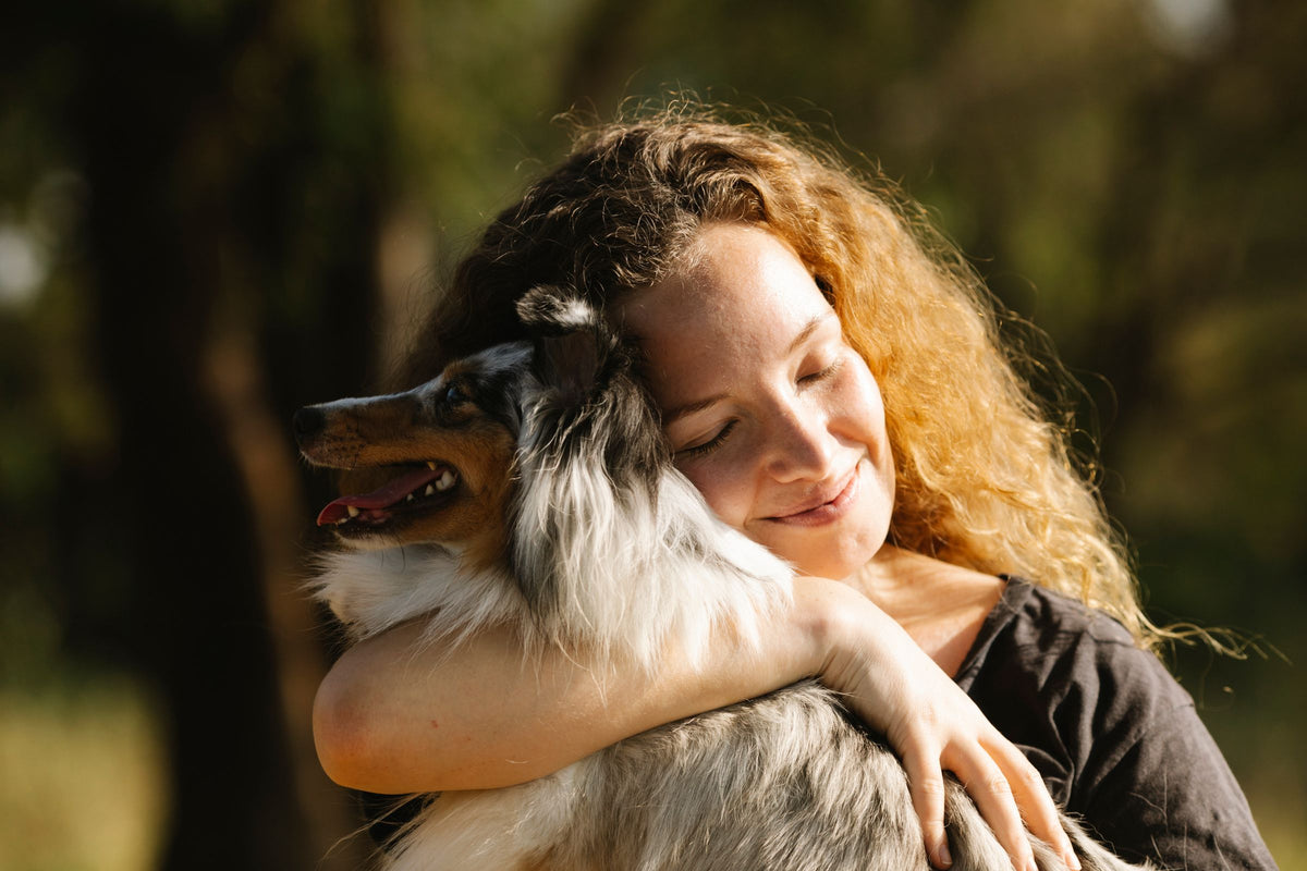 Woman holding her dog close in warm afternoon light